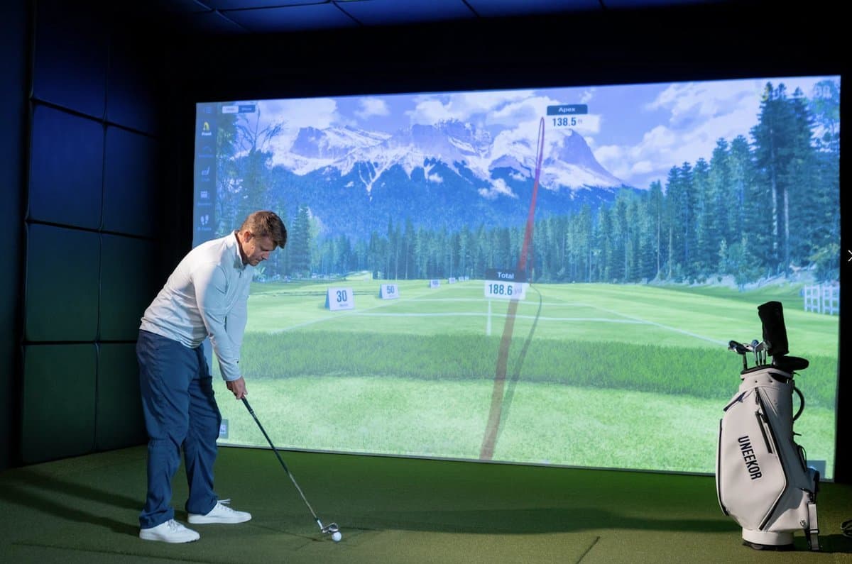 Uneekor QED launch monitor with GameDay software interface showing realistic golf course graphics and shot data