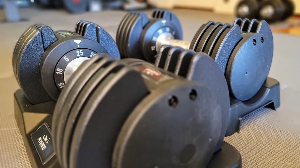 Adjustable dumbbells with various weight plates in home gym setting